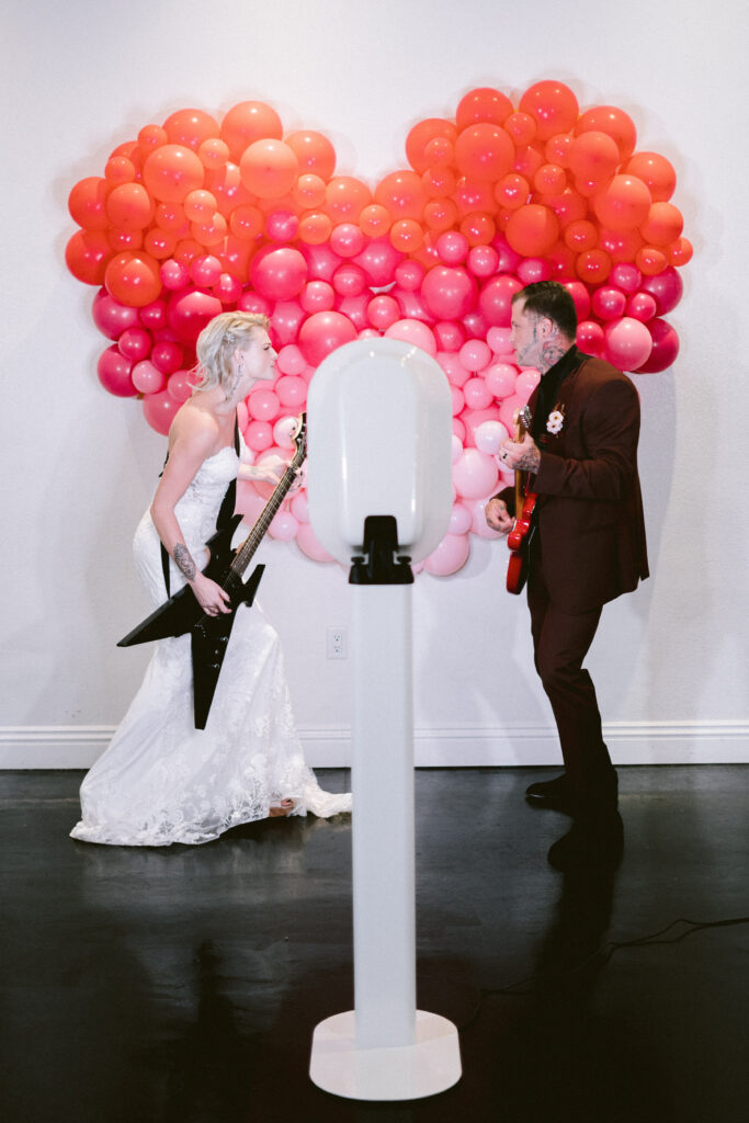 wedding couple playing music in front of balloon backdrop at wedding
