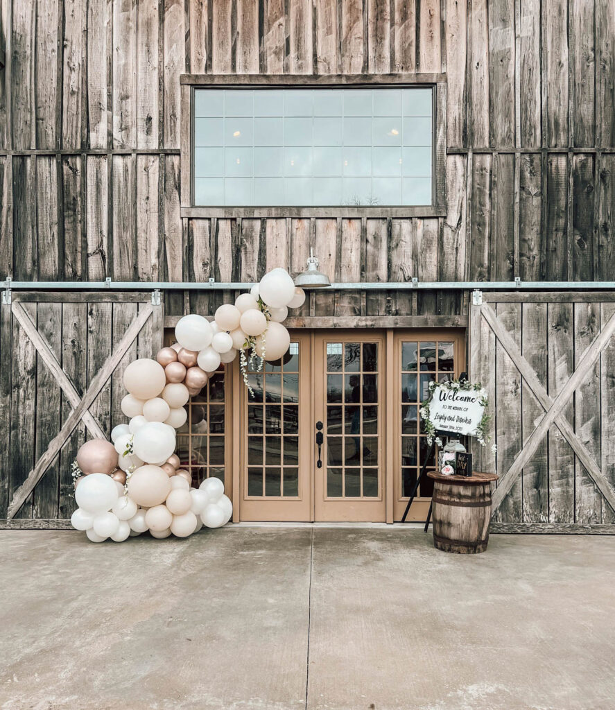 Rustic barn entrance with a chic balloon arch in neutral tone