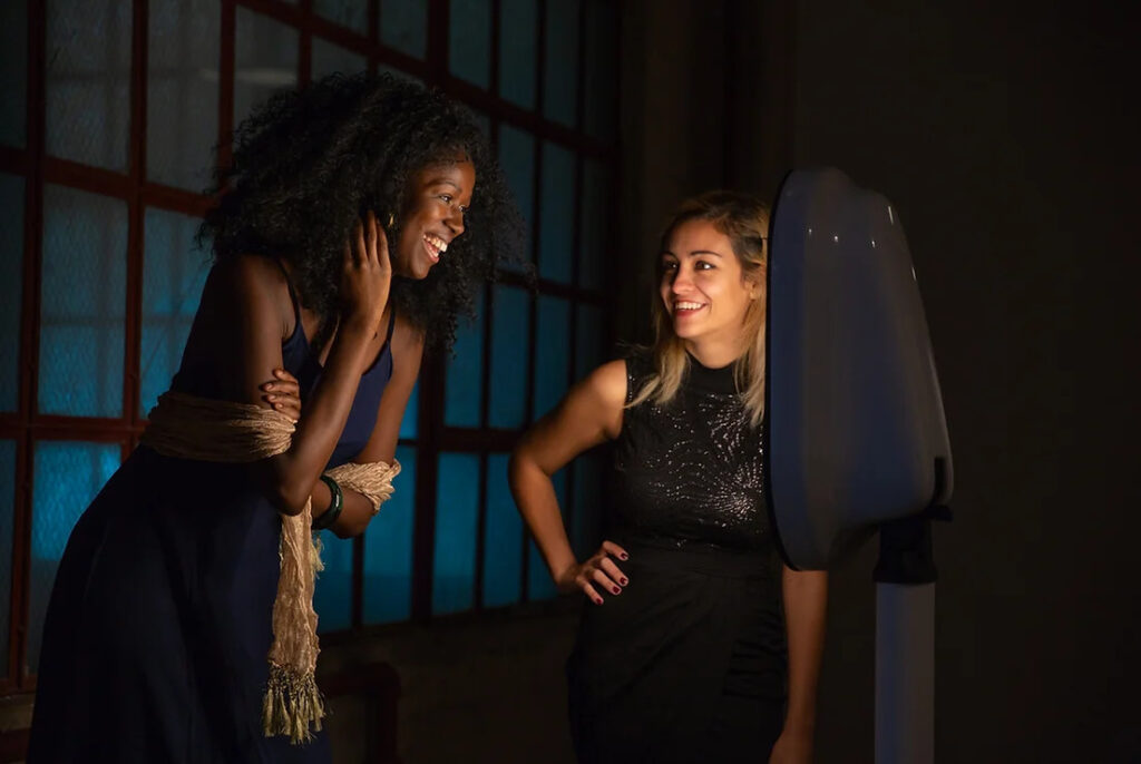 two ladies smiling at each other getting ready to take a photo on a photo booth