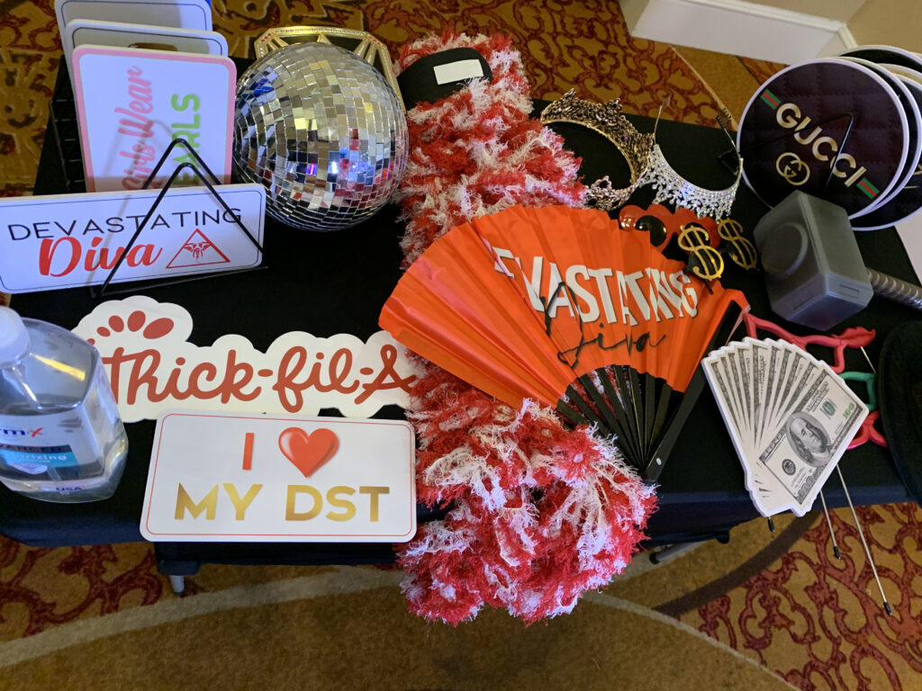 Table setup featuring vibrant and unique photo booth props, including a disco ball, novelty signs, fans, and playful accessories