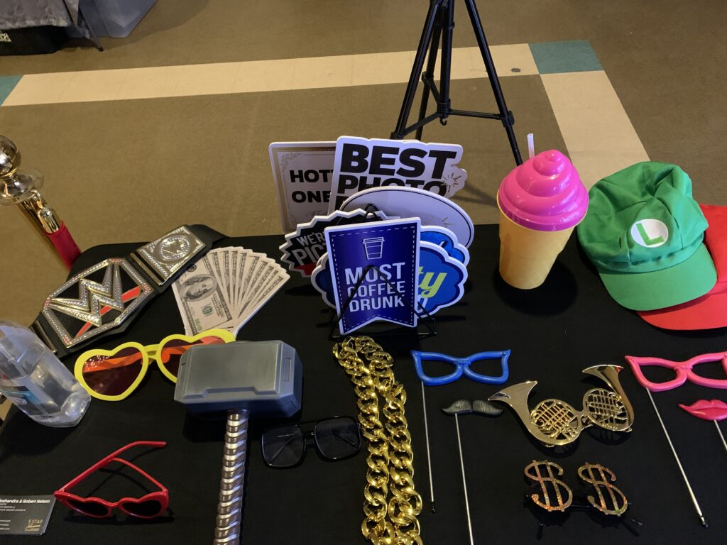 Photo booth prop display with colorful hats, novelty glasses, championship belt, and witty signs for a fun guest experience