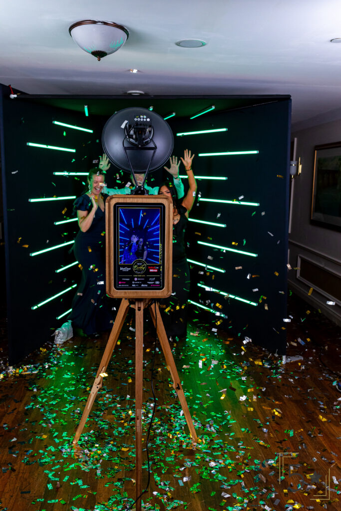 Photo booth with neon green backdrop and confetti-covered floor