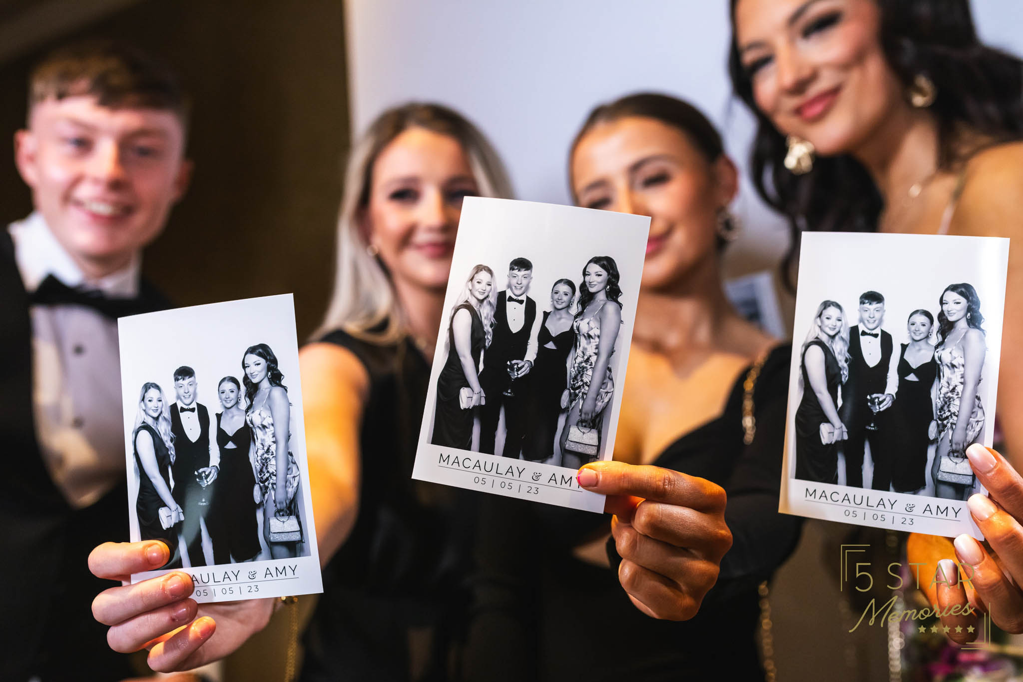 people holding up glamour photo booth photos
