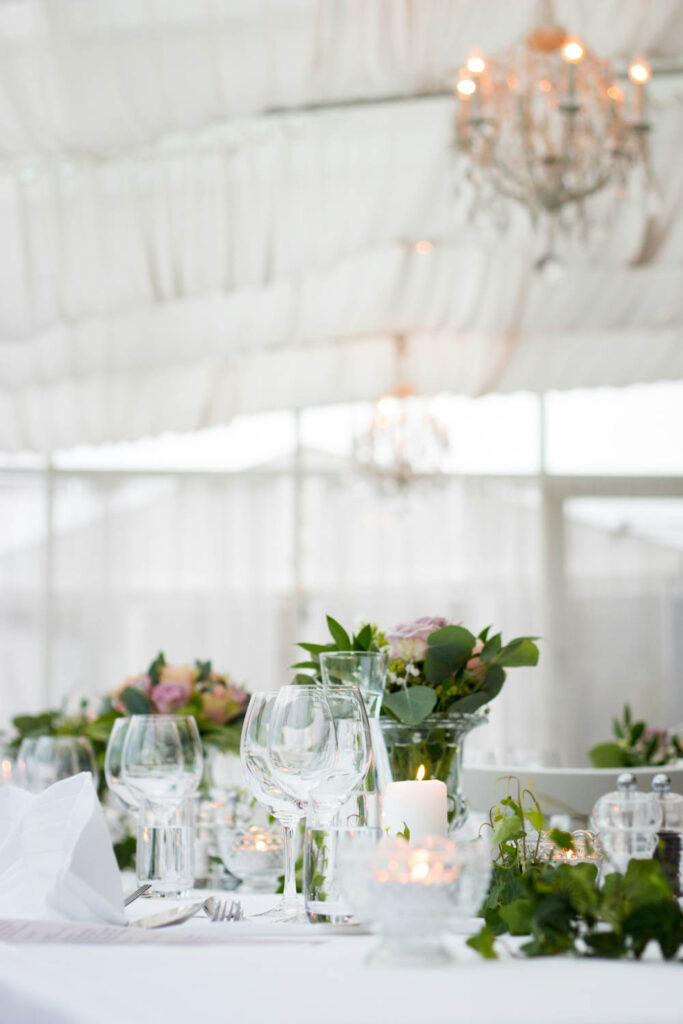 table setting under chandeliers, with floral arrangements, candles, and crystal glassware.